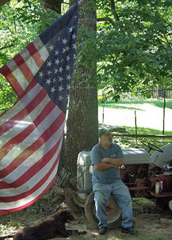 Alzheimer advocate Amy’s dad sitting on a tractor with Amy's dog Layla lying by his feet.
