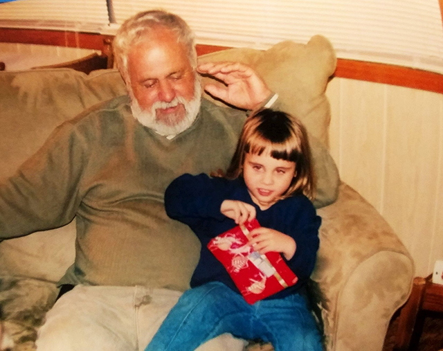 Amy's daughter sitting on Amy's dad's lap opening a present