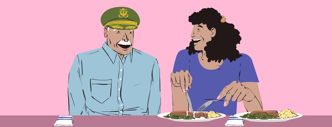An elderly man wearing a US Army colonel's hat sits with a younger woman. She is cutting up meat on a plate of food next to another plate of the same food that is uncut.