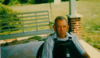 Middle-aged man in a chair on a porch, in an older color photograph.