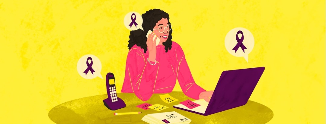 A woman sits at a desk talking on a cell phone and typing on a laptop. The desk is covered with Post-It notes, a stack of envelopes, a pencil, and a telephone. Both phones and the laptop have speech bubbles with purple awareness ribbons inside them.