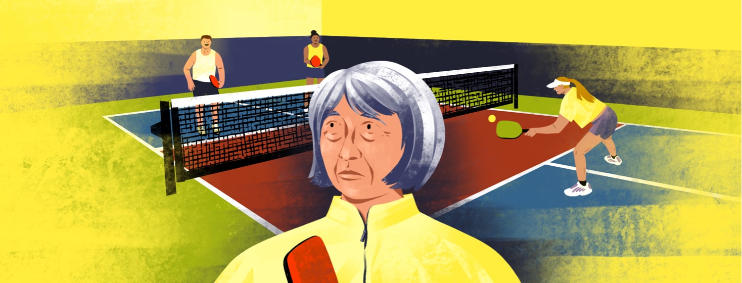 alt=An older woman looks confused. Behind her are people playing on a pickleball court.
