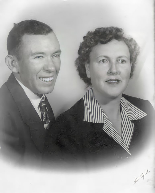 An old black and white photograph of a married couple smiling for the camera.