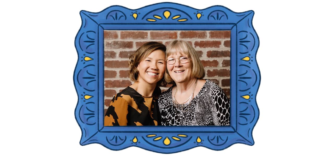 Two women in front of a brick wall in a blue ornate frame