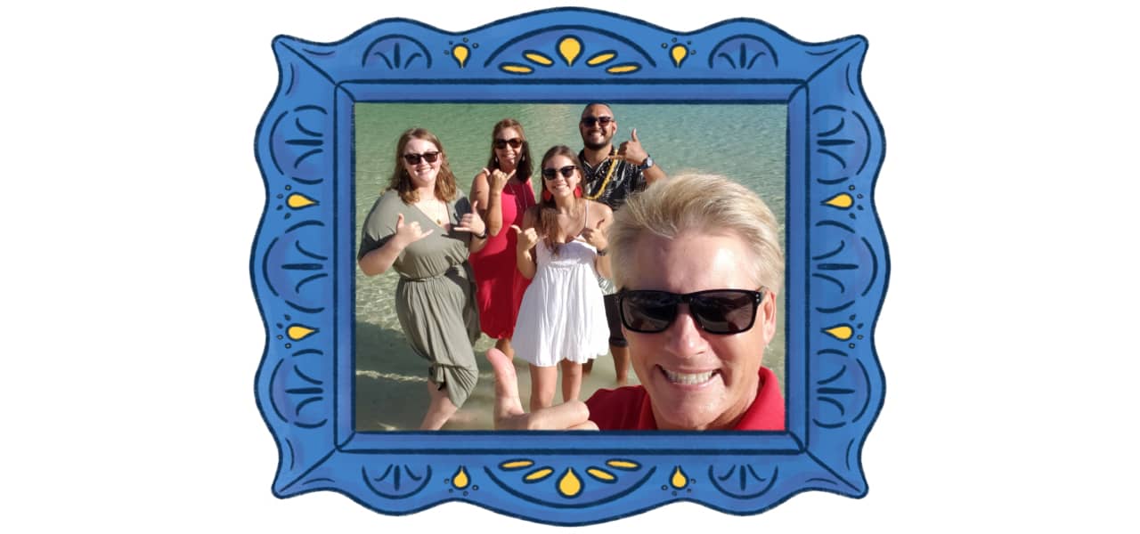 A man giving a thumbs up in front of his family in a blue picture frame