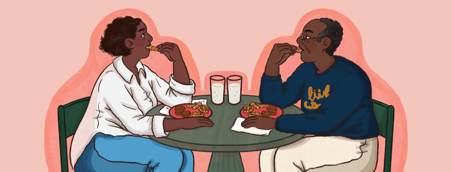 Two people sit across from each other at a table eating, their body positions mirror each other