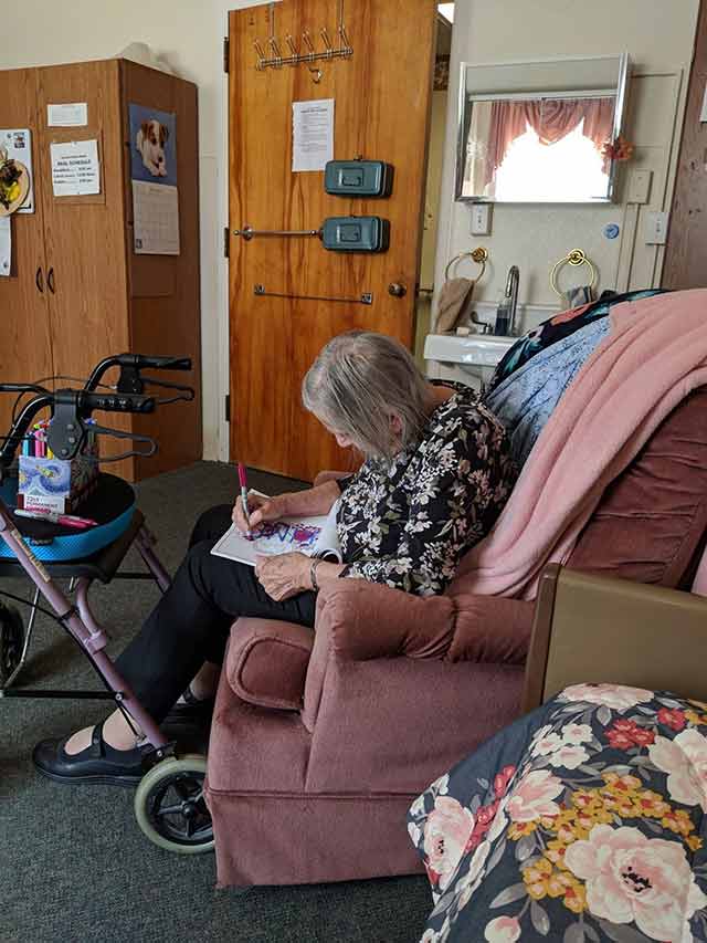 Joan sitting in a chair coloring an image.