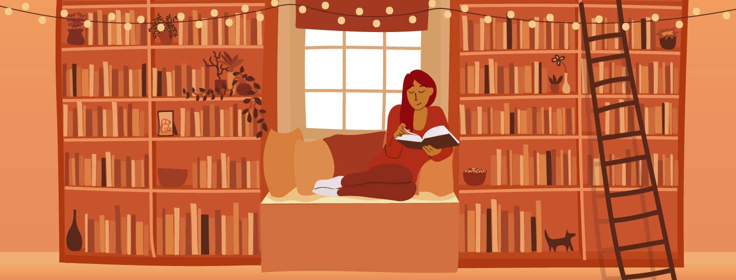 Woman reading book in front of window between bookshelves